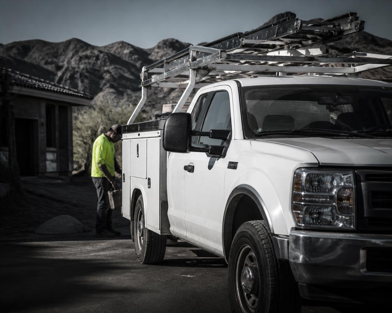 Contractor loading tools into a commercial service truck at an Arizona job site